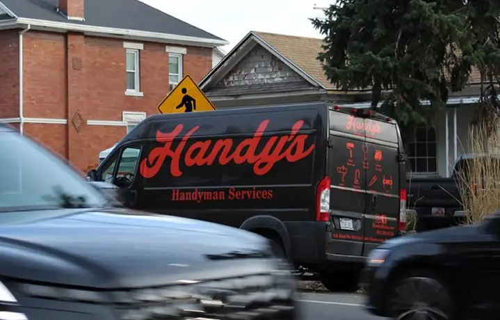 The Handy's van parked on a Salt Lake City street in late fall, bare trees behind a brick house