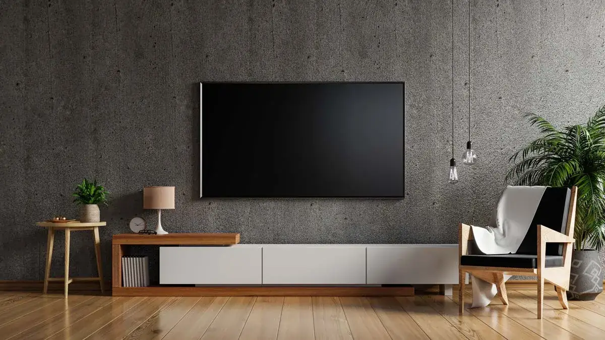 A large TV mounted flat on a concrete wall above a low media console